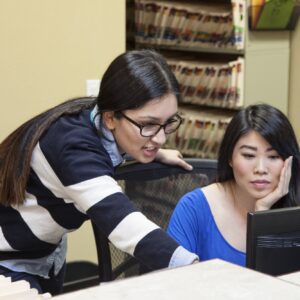 Asian woman and east indian woman working on a computer in a medical office.